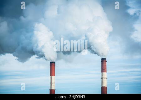 Closeup view steam coming out of pipes of thermoelectric power station in winter time.Termal power industry and environmental pollution concept and . Stock Photo