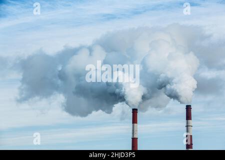 Steam coming out of pipes of thermoelectric power station in winter time. Termal power industry and environmental pollution concept and . Stock Photo