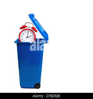 Alarm clock in the dustbin, symbolic of wasting time Stock Photo