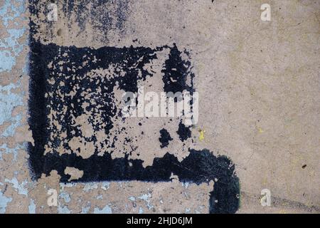Old beige black paint with cracks on brick wall as background, texture, selective focus Stock Photo