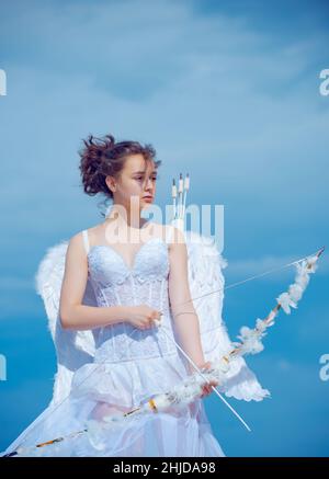 Valentin angel teen girl in white angels dress with wings. Valentines teenager girl with bow arrow. Stock Photo