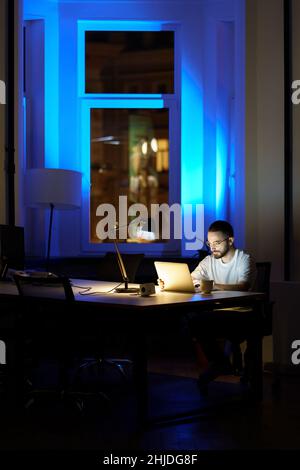 Thoughtful young businessman in glasses work on laptop at night preparing for startup presentation Stock Photo