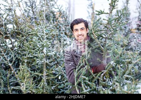 handsome russian man shopping for christmas tree outdoors market Stock Photo