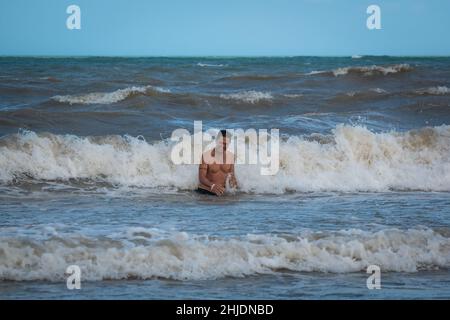 Palomino, Dibulla, La Guajira, Colombia - December 4 2021: Young Latin Man Swims in the Ocean with his Eyes Closed near to the Seashore Stock Photo