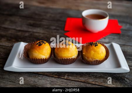 Traditional Chinese New Year pastries baked with fluffy dough and filled with salted egg yolk and sweet paste. Chinese lucky money red packets and tea Stock Photo