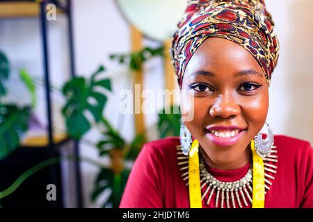 tanzanian woman with snake print turban over hear working in dressmaking shop Stock Photo