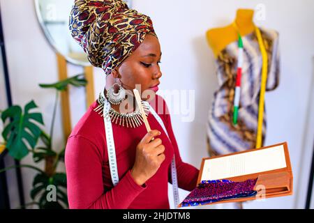 latin hispanic woman with fashionable turban over head and red dress working in clothess making office Stock Photo