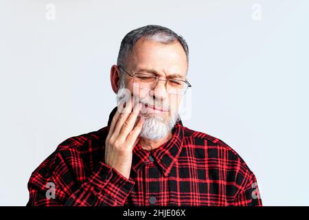 Portrait of mature man isolated on grey background studio suffering from severe dental ache , closing eyes to relieve pain Stock Photo