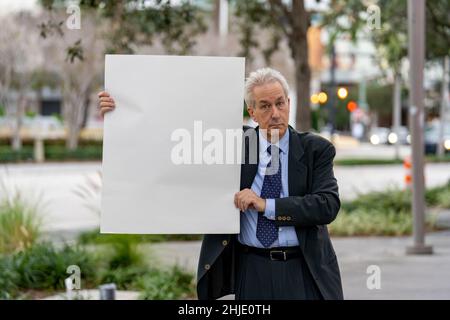 Businessman holding up a blank white paper sign Stock Photo