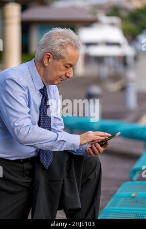 Mature businessman in a blue shirt sending messages on his smart phone Stock Photo