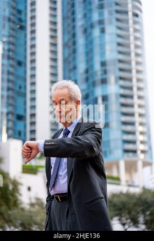 Mature old businessman checking the time on his watch Stock Photo