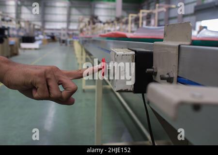 Male hand pushing emergency red stop button. Stock Photo