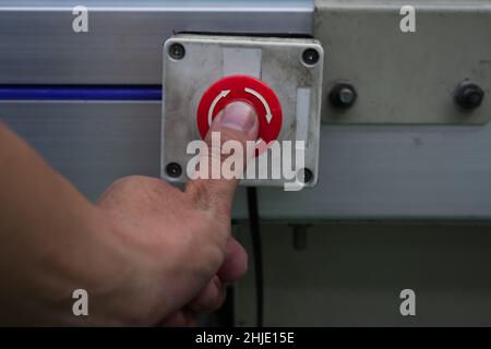Male hand pushing emergency red stop button. Stock Photo