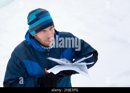 Portrait of a master in blue overalls and a blue knitted hat with sheets of paper in his hand Stock Photo
