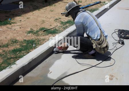 Builder worker with cut-off machine power tool breaking asphalt at road construction site Stock Photo