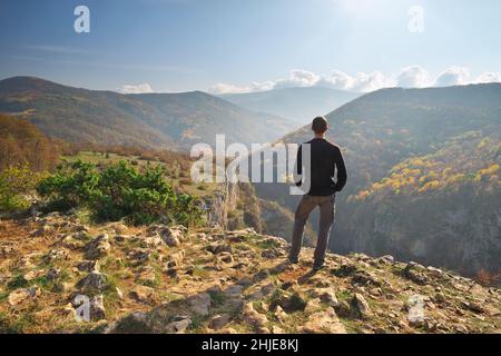 Man standing on the cliff. Conceptual scene. Mountain nature composition. Stock Photo