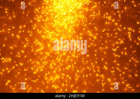 Defocused golden glitter. Glowing holiday bokeh background Stock Photo
