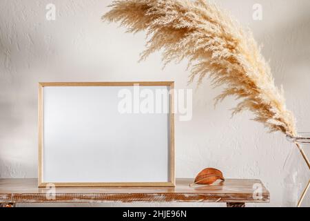 30x40 cm photo frame on a bench with pampas grass near the wall Stock Photo
