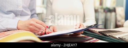 Two women choose fabrics and place order in store closeup Stock Photo