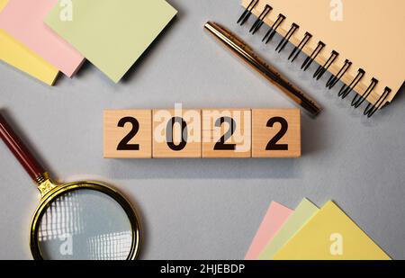 2022 for business and education concept. New year inscription, numbers on wooden cubes over desk with stationery. Stock Photo