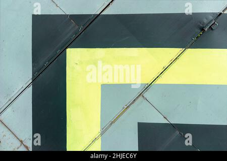 Abstract yellow, grey and black geometric lines on metal wall, architecture. Stock Photo