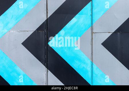 Abstract repeating blue, black and gray arrows on building wall. Strategy and direction concept. Stock Photo