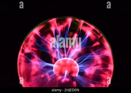 Plasma ball with iridescent lightning in different colors on a very dark background Stock Photo