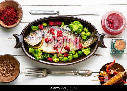Delicious sea bream baked with raspberries and broccoli. Stock Photo