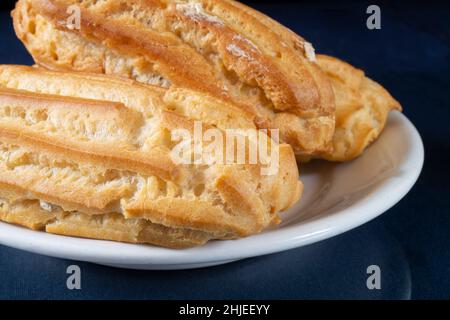 Sweet pastries in a white plate on a black background. Delicious delicacy close-up Stock Photo