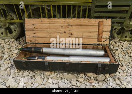 Shells for the tank in a green wooden box on the rocks near the tank. Supply of military ammunition. Stock Photo