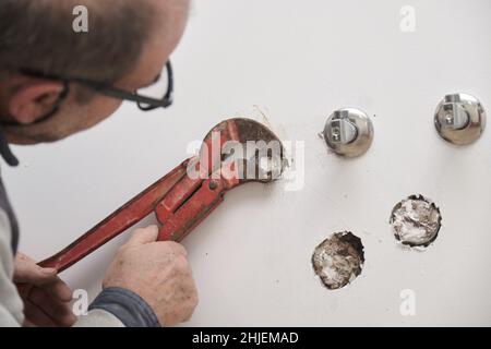 Senior plumber using slip joint pliers to unscrew the fitting on a pipe. Stock Photo