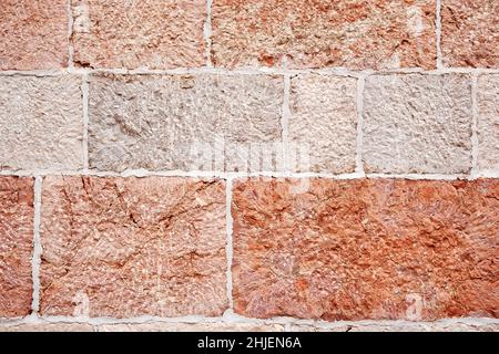 Textured of an old wall with many pink and peach stone tiles. Traditional European architecture. Stock Photo