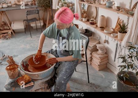 Young female artisan concentrated on modeling bowl in workroom Stock Photo