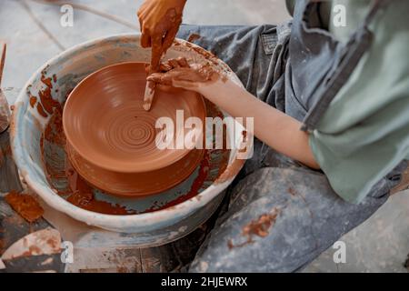 Young potter working on potter wheel in workroom Stock Photo