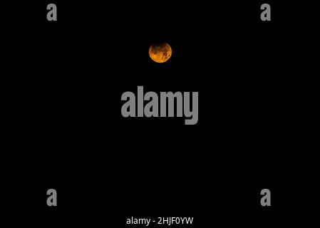 Landscape image of partial lunar eclipse during November 2021 which conincided with blood red moon phoase Stock Photo