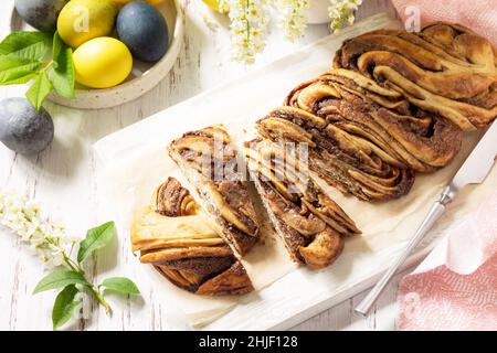 Easter baking. Homemade Easter Chocolate babka or brioche bread. Sweet yeast dough with chocolate filling and accompanied and nuts on a wooden table. Stock Photo
