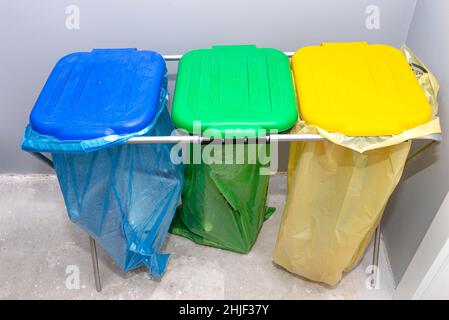 https://l450v.alamy.com/450v/2hjf37y/three-garbage-bags-for-segregating-glass-foil-and-paper-standing-on-a-rack-in-the-garage-with-the-lid-closed-2hjf37y.jpg