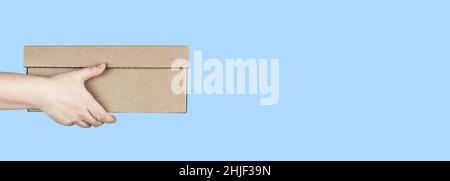 Large cardboard box in hands on blue background Stock Photo
