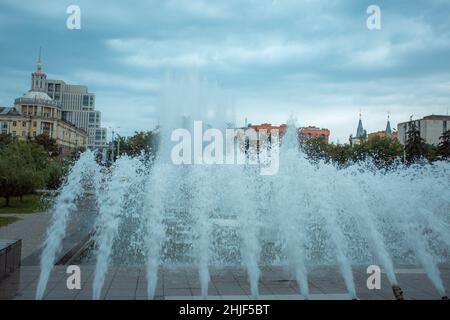 The jets of the fountain beat against the backdrop of a stormy sky. Drops of water against the background of clouds and blue sky. Spray from the city Stock Photo