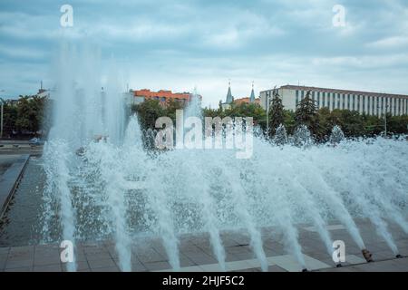 The jets of the fountain beat against the backdrop of a stormy sky. Drops of water against the background of clouds and blue sky. Spray from the city Stock Photo