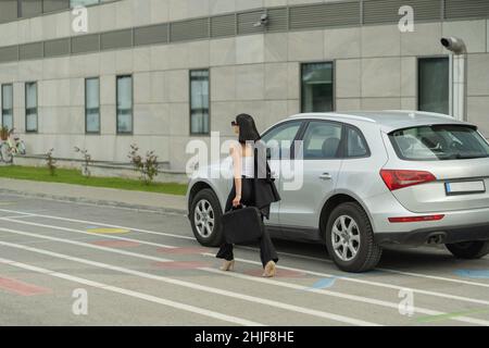 Attractive businesswoman is walking past her business car Stock Photo