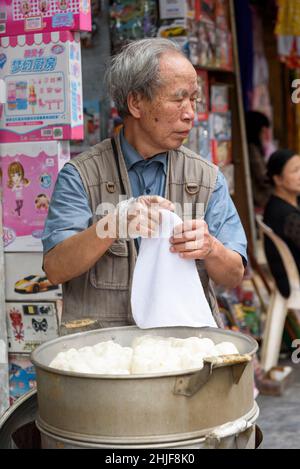 An old Vietnamese man sells food on the streets of the Old Quarter of Hanoi, Vietnam, Southeast Asia Stock Photo