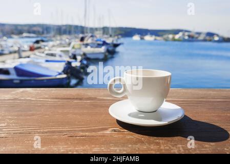 Coffee cup on a wood table over blue sky and sea background. Summer fun, enjoying life, vacations, holidays, tourism, travel concept Stock Photo