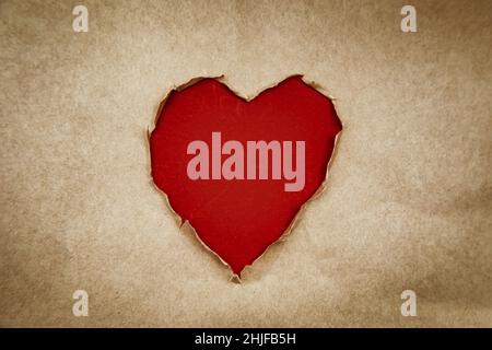 Hole in the shape of a heart. Recycled kraft paper. Vintage, grunge style, copy space. Valentine's day concept. Stock Photo