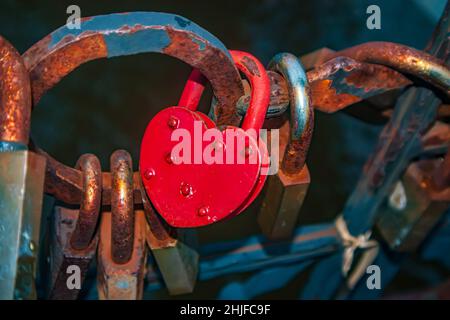Rusty love red romantic lock on a bridge. Russia, Kaliningrad - January 16, 2022. Stock Photo