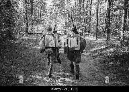 Two Re-enactors Dressed As World War II Russian Soviet Red Army Soldiers Marching Through Forest. Photo In Black And White Colors. Soldier Of WWII WW2 Stock Photo