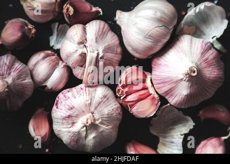 Garlic bulbs and garlic cloves on a black background. Close-up, flat lay, top view. Food background, selective focus. Stock Photo