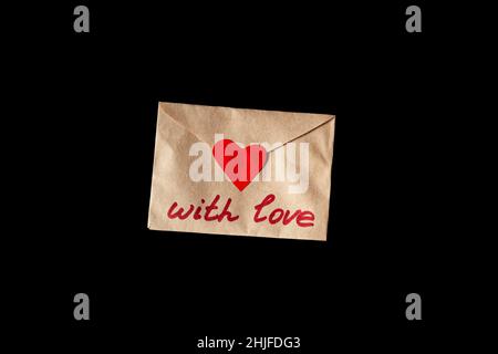 Letter valentine on black background. The inscription "With love" and a heart on the envelope from craft paper. Stock Photo