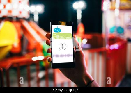 Artificial intelligence chat bot concept, female hand holding smartphone with online AI robot assistant and voice message icon Stock Photo