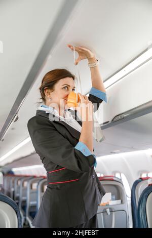 Stewardess demonstrating how to use oxygen mask in aircraft Stock Photo